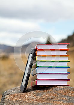 Stack of printed books with electronic book reader