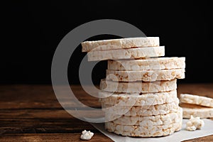 Stack of puffed rice cakes on wooden table against background. Space for text