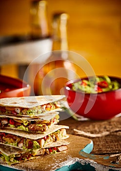 Stack of quesadillas with beer and bowl