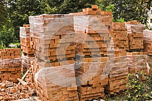 Stack of red brick for construction. Common quality building bricks stacked ready for use.