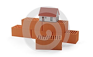 Stack of red brick stones with model miniature house on top on white background, construction or masonry or industry concept