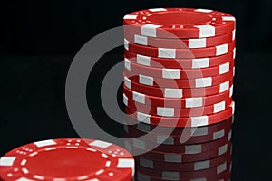Stack of red casino chips on black background with reflection