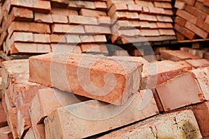 A stack of red clay bricks in rows close up.