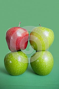 Stack of red and green apples over colored background