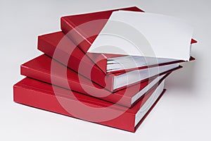 Stack of red hardcover books or reports with empty sheet of paper on the top, on white background.