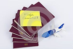 A stack of red passports, Note Flight Cancelled and small airplane toy isolated on White Background . Travel concept