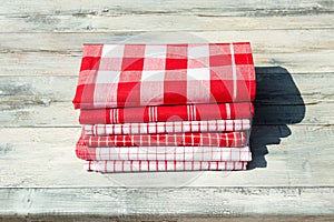 Stack of red white checkered and striped tableclothes on rustic