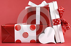 Stack of red and white polka dot theme festive gift box presents with white heart