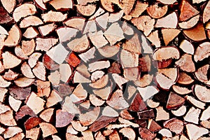 Stack of reddish natural firewood in preparation for the winter and used for camp fires, fireplaces and home heating.