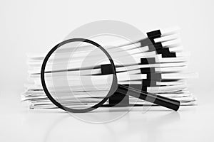 Stack of report paper documents with magnifying glass. Concept of business and search