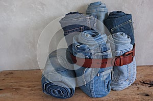 Stack roll blue denim jeans and Leather Belt on wood