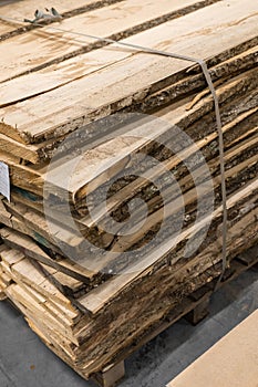 A stack of rough-cut lumber sits on a wooden pallet.