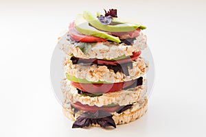 Stack of round crispbreads with cheese, tomatoes, avocado and basil