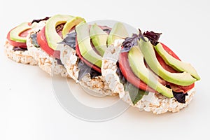 Stack of round crispbreads with cheese, tomatoes, avocado and basil