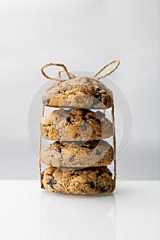 Stack of round oatmeal or chocolate chip cookies tied with a rope on reflective surface over white background