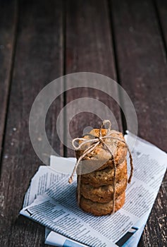 Stack of round oatmeal or chocolate chip cookies tied with a rope on wooden rustic background