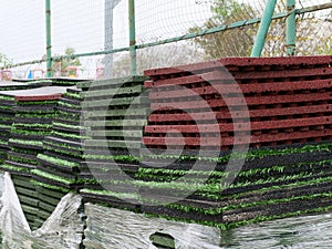Stack of rubber floor tile mats and artificial turf grass rug tiles for elastic safety flooring. Eco safety surfacing mats are a