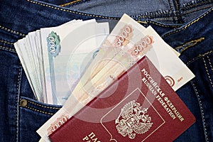 A stack of Russian five-thousandth and one thousand-ruble bills in a pocket of blue jeans and a Russian international passport.