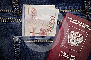 A stack of Russian five-thousandth and one thousand-ruble bills in a pocket of blue jeans and a Russian international passport.