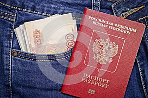 A stack of Russian five-thousandth and one thousand-ruble bills in a pocket of blue jeans and a Russian international passport.