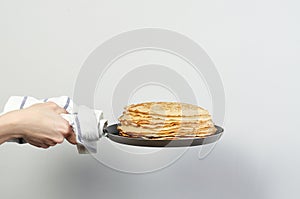 Stack of russian pancake blini in pan woman holds in hands
