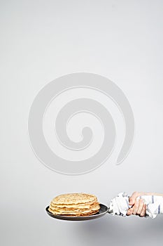 Stack of russian pancake blini in pan woman holds in hands