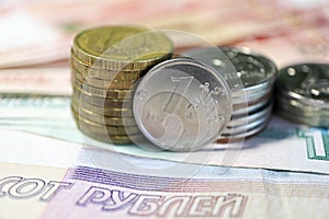 Stack of russian roubles coins on the banknotes background closeup