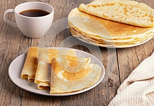 Stack of Russian thin pancakes and coffee on a wooden table