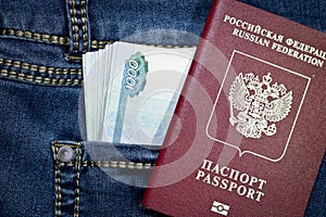 A stack of Russian thousand-ruble bills in a pocket of blue jeans and a Russian international passport. Money in your pocket, cash