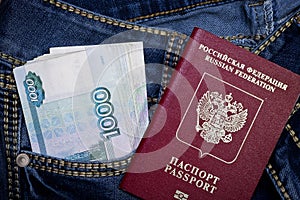 A stack of Russian thousand-ruble bills in a pocket of blue jeans and a Russian international passport. Money in your pocket, cash