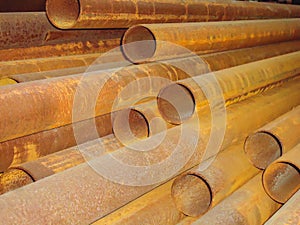 Stack of rusty steel pipes in an industrial warehouse