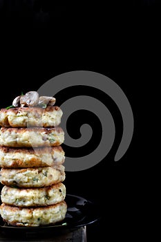 Stack of salty syrniki with champignons and herbs