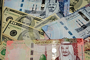 Stack of Saudi Arabia riyals money banknote bills with United States of America dollars background