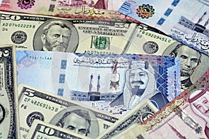Stack of Saudi Arabia riyals money banknote bills with United States of America dollars background
