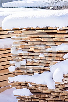 Stack of sawn planks covered with snow