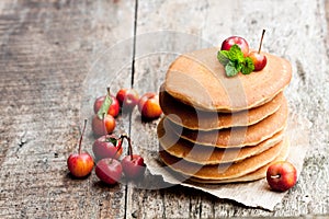 Stack of scotch pancakes with fresh wild apples on wooden table