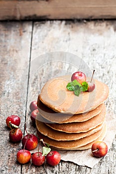 Stack of scotch pancakes with fresh wild apples on wooden table