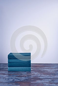 A stack of several books in fabric textured covers in a beautiful emerald color on an old wooden table.