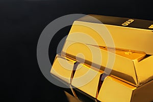 Stack of shiny gold bars on black background. Space for text