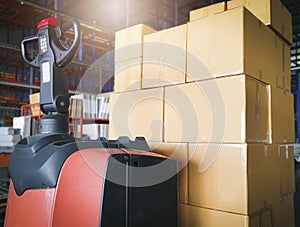 Stack of shipment cardboard boxes with electric forklift pallet jack at manufacturing warehouse storage. Cargo export