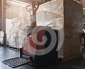 Stack of shipment cardboard boxes with electric forklift pallet jack at warehouse storage. Cargo export & shipping warehousing.