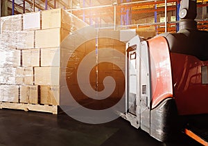 Stack of shipments boxes on wooden pallets and Electric forklift pallet jack at the warehouse storage.