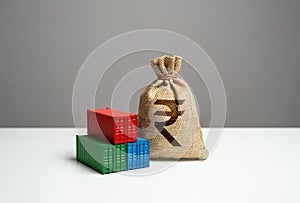 Stack of shipping containers and indian rupee money bag. GDP and production.