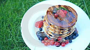 Stack of small pancakes in syrup on green background