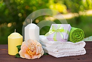 Stack of soft towels, fragrant rose, a candle and a small box with a gift. Spa concept. Romantic concept.