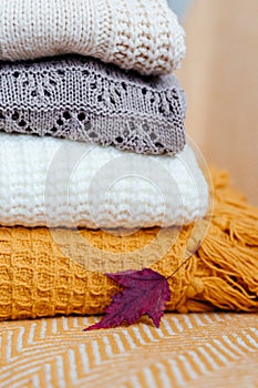 Stack of soft warm plaids and an autumn leaf close-up.