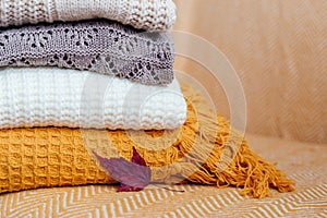 Stack of soft warm plaids and an autumn leaf close-up.