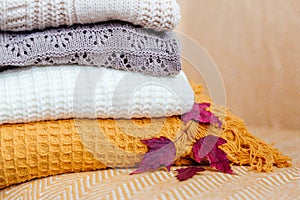 Stack of soft warm plaids and an autumn leaves close-up.