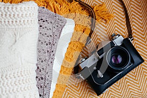 Stack of soft warm plaids and retro camera, top view.