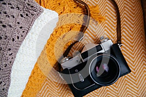 Stack of soft warm plaids and retro camera, top view.